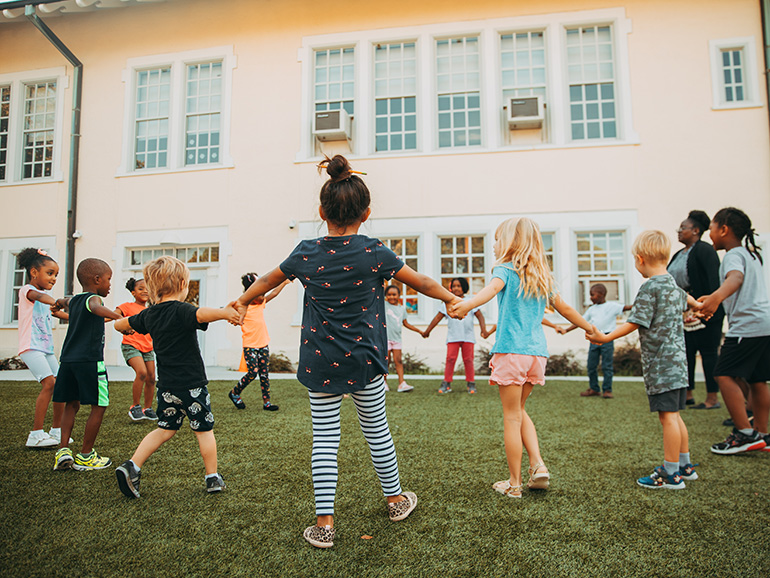 niños y niñas cogidos de la mano en círculo